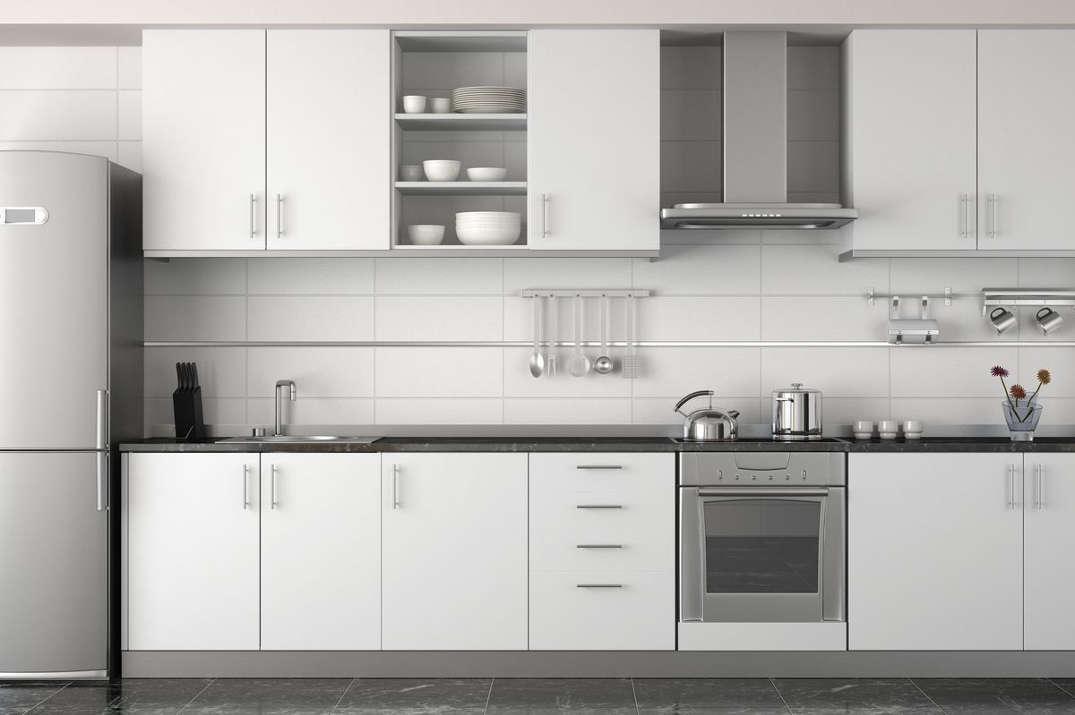 Cocina blanca en línea con encimera negra, campana y frigorífico de acero inoxidable