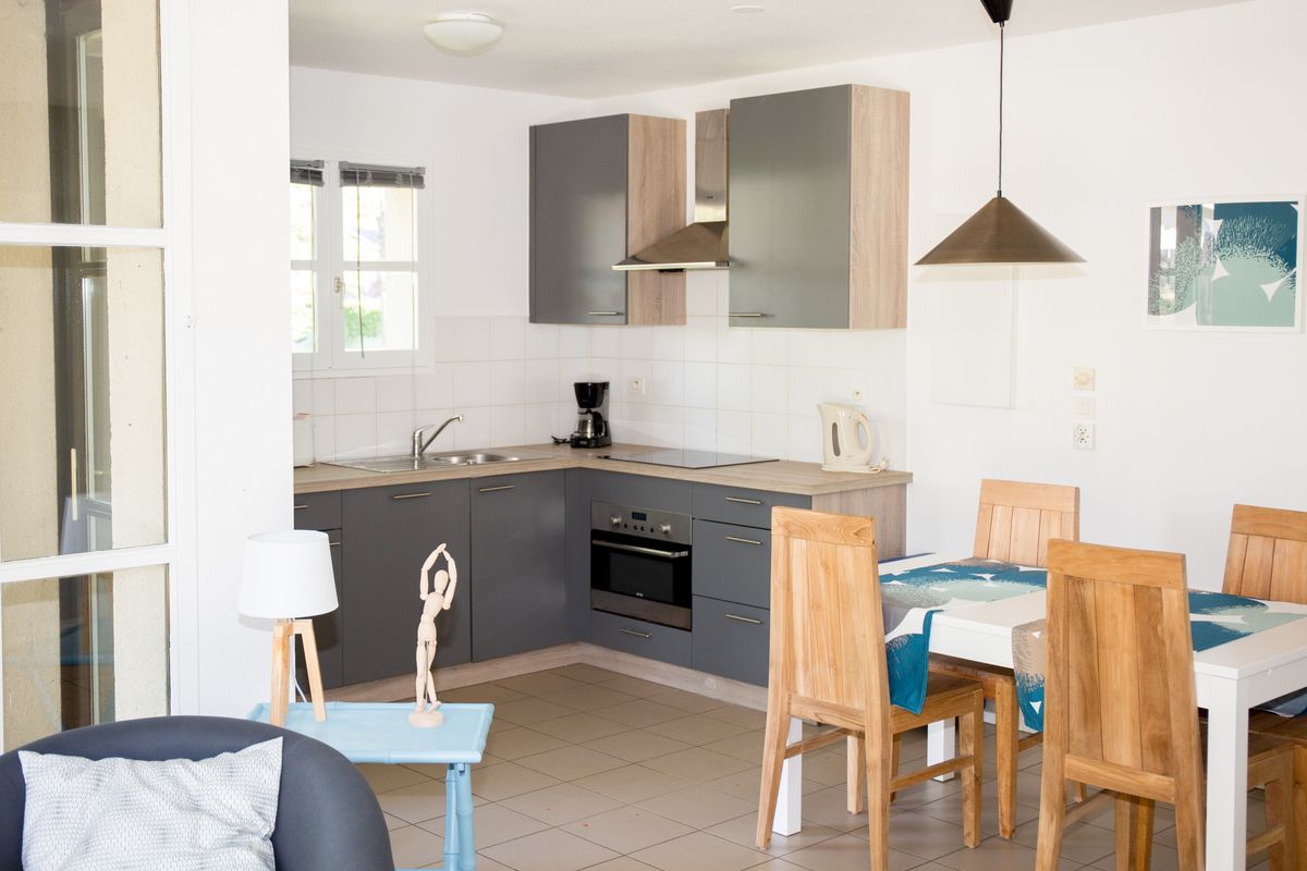 Cocina en L con muebles grises y madera, abierta al comedor de una vivienda